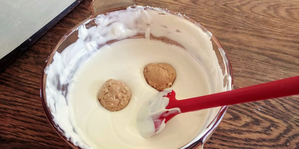 The Best Peanut Butter BonBons dipping white bonbons in bowl