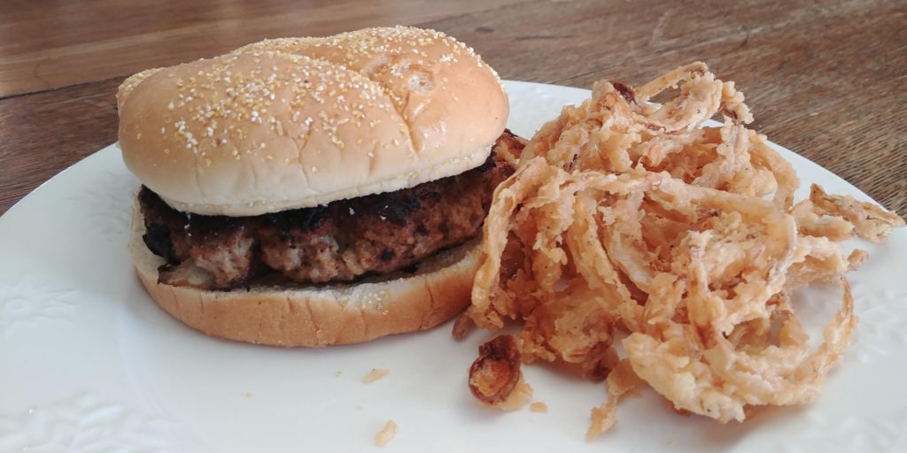 Crispy Onion Strings on plate with burger
