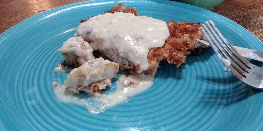 Turpin Breaded Pork Chops on plate with gravy cut